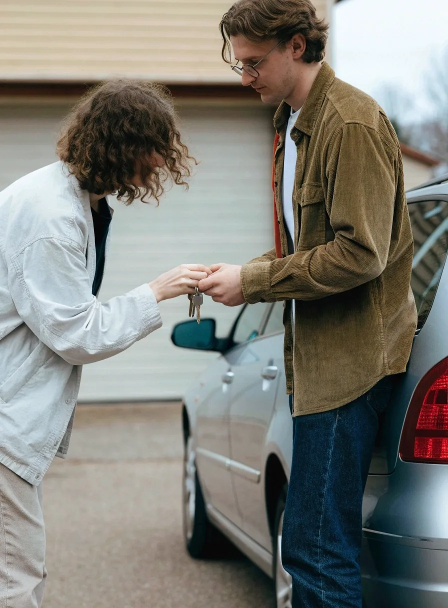 A buyer and seller checking a used car together at a petrol station forecourt